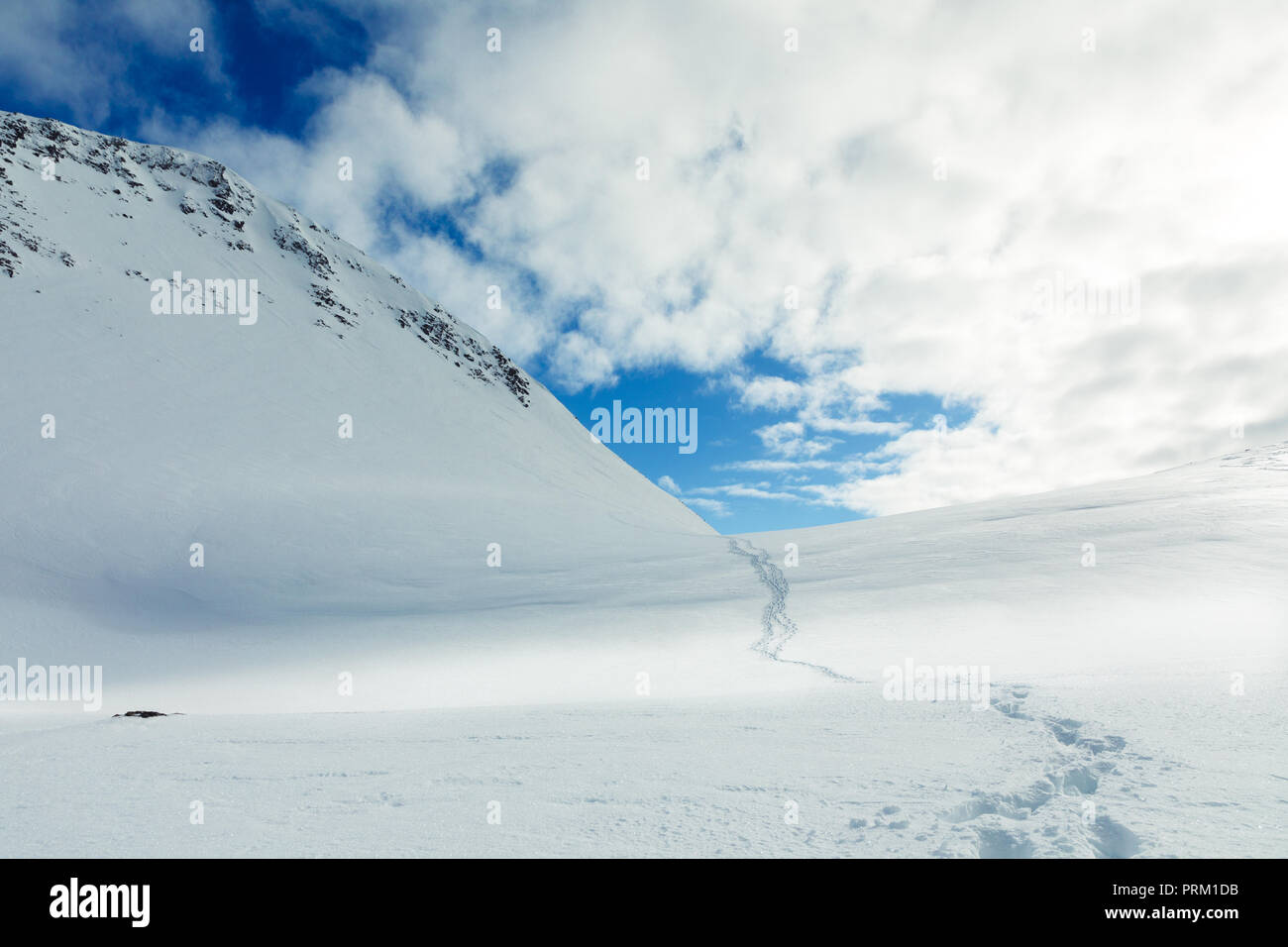Le vie che conducono una coperta di neve montagna con drammatica blue skies in Norvegia. Foto Stock