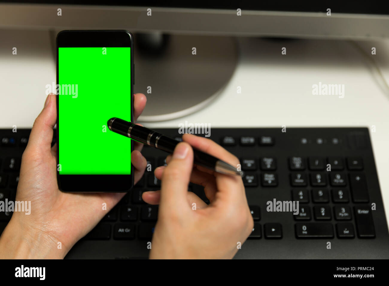 Le mani delle donne tocca lo schermo del telefono con la penna per il touchscreen. Telefono cellulare con una schermata verde. Foto Stock
