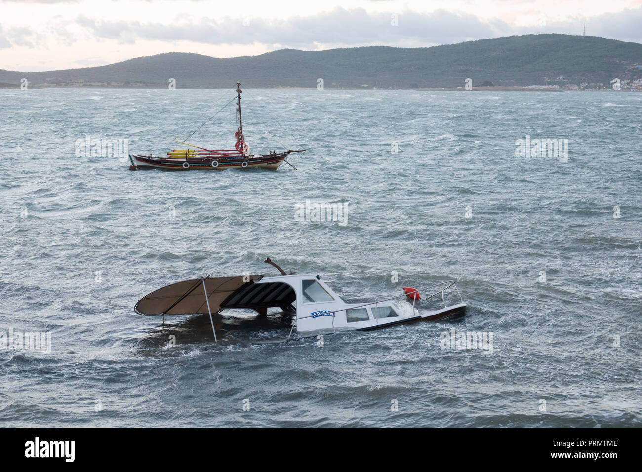 Barca ormeggiata parzialmente affondato dalla Forza di tempesta si snoda sulla costa del Mar Egeo a Ayvalik, Turchia Foto Stock