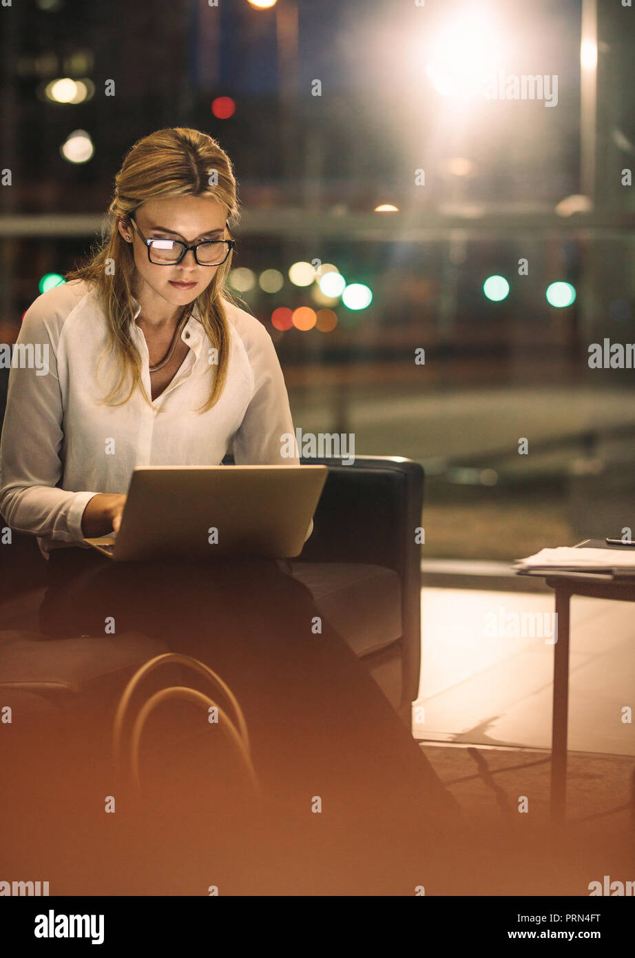 Giovane donna lavora fino a tardi sul computer portatile in ufficio. Business femmina professionale di lavoro nel corso del tempo in ufficio per completare il progetto. Foto Stock