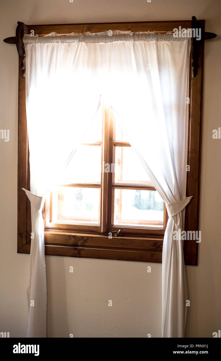 Una finestra in legno con tende bianche Foto Stock
