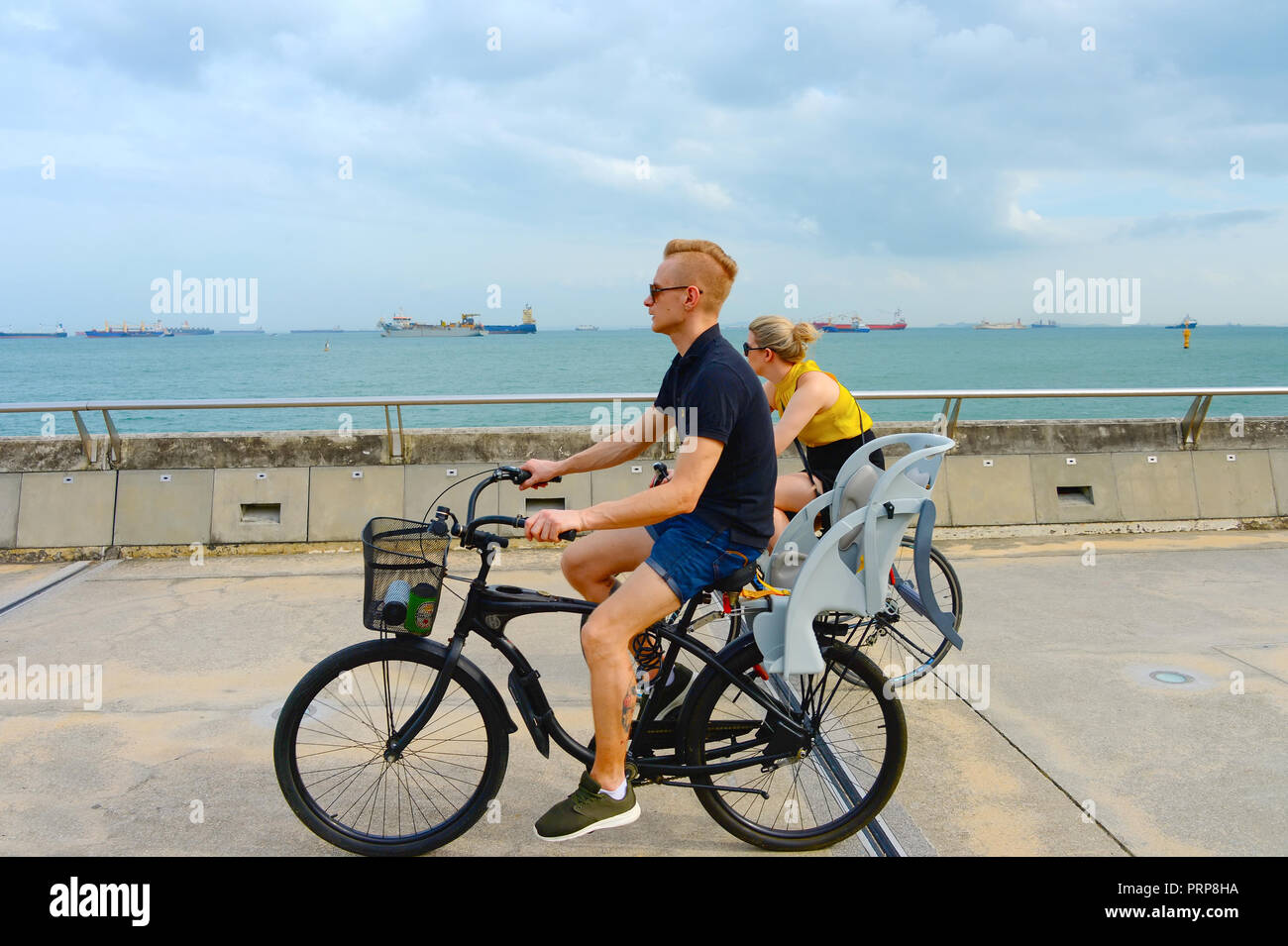 SINGAPORE - Febbraio 6, 2017: giovane equitazione biciclette al porto di Singapore. Singapore è un importante hub finanziaria in Asia Foto Stock