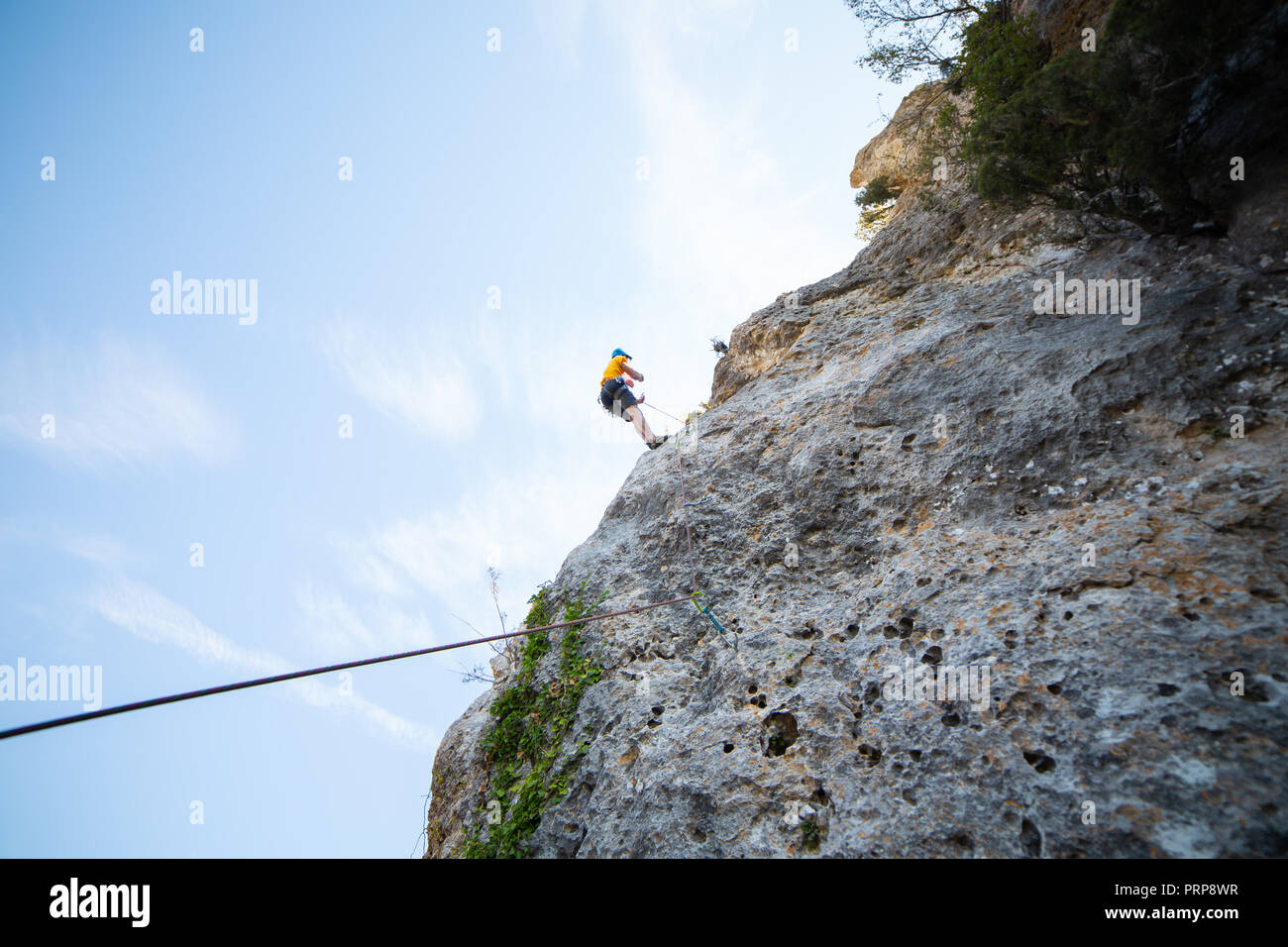 Da sotto tiro dei maschi di scalatore arrampicata in montagna sulla parete incredibile giornata di sole Foto Stock