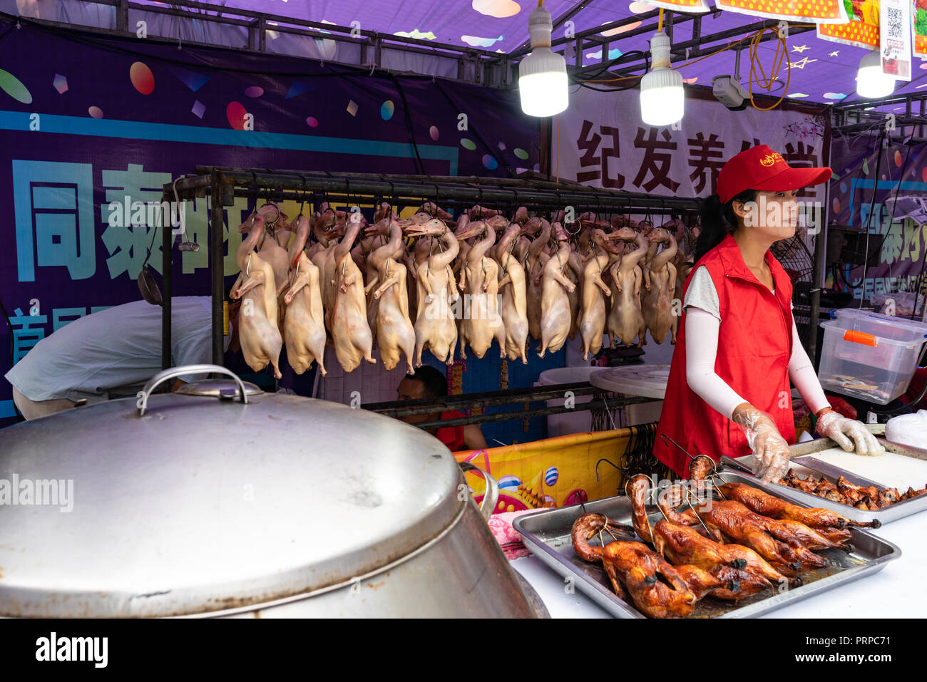 Anatre spennate in una fila in corrispondenza di un supporto alimentare in Cina Foto Stock