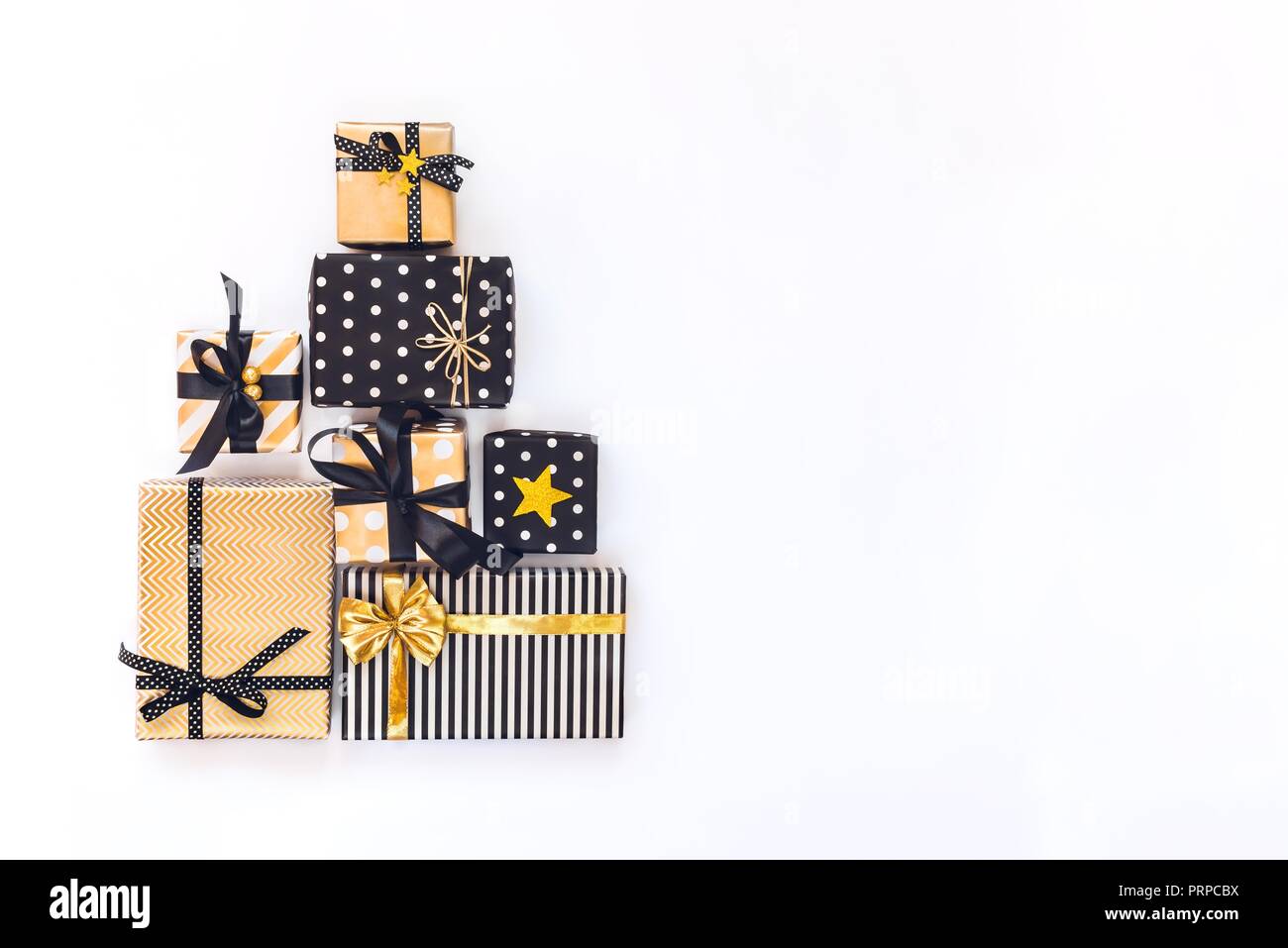 Vista superiore delle confezioni regalo in vari nero, bianco e golden disegni disposti in forma triangolare come albero di Natale o la torta di compleanno. Un concetto di Chri Foto Stock