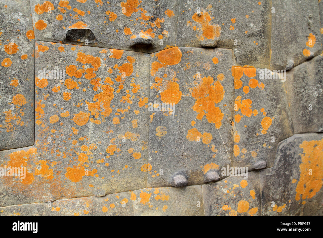 Tempio Inca muro di pietra fatta con perfettamente equipaggiato pietre ricoperto di lichene arancione Foto Stock