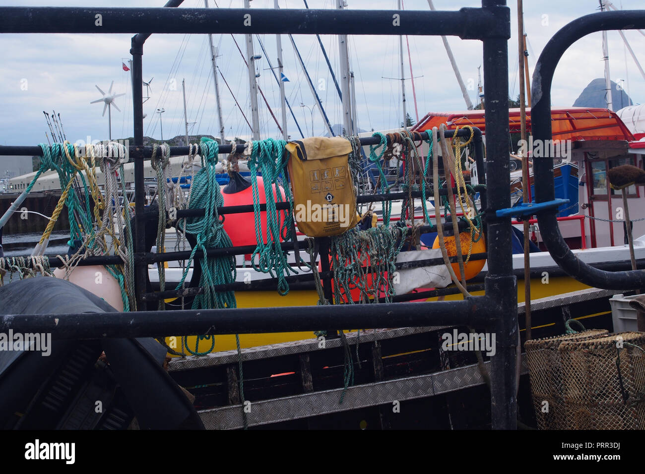 Funi, netting un sacchetto e nodi legato al metallo ringhiere di una piccola barca da pesca ormeggiate nel porto a Lochinver, Scozia Foto Stock