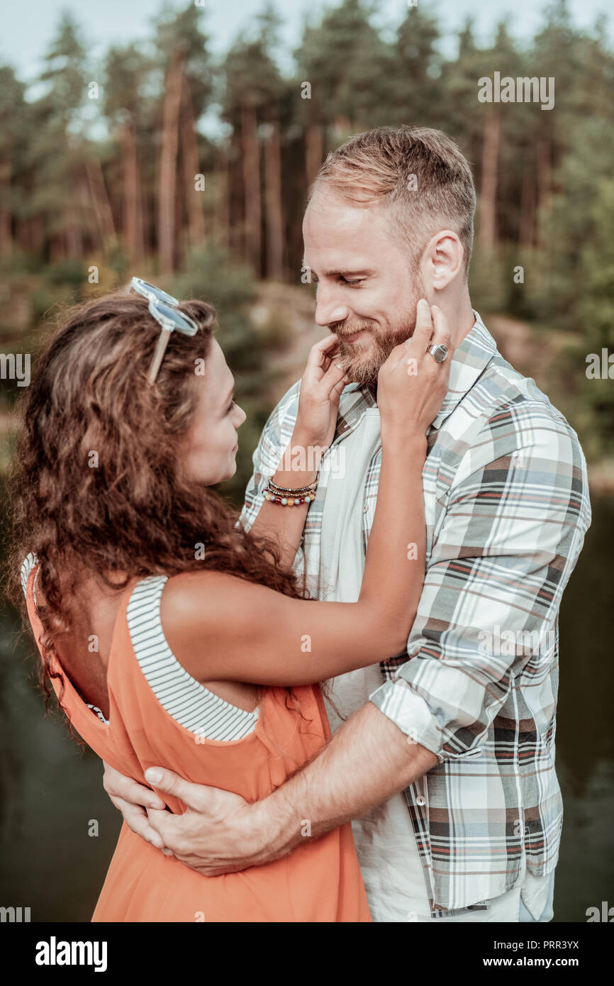 Bionda uomo barbuto alimentano incredibile mentre abbracciando attraente donna ricci Foto Stock
