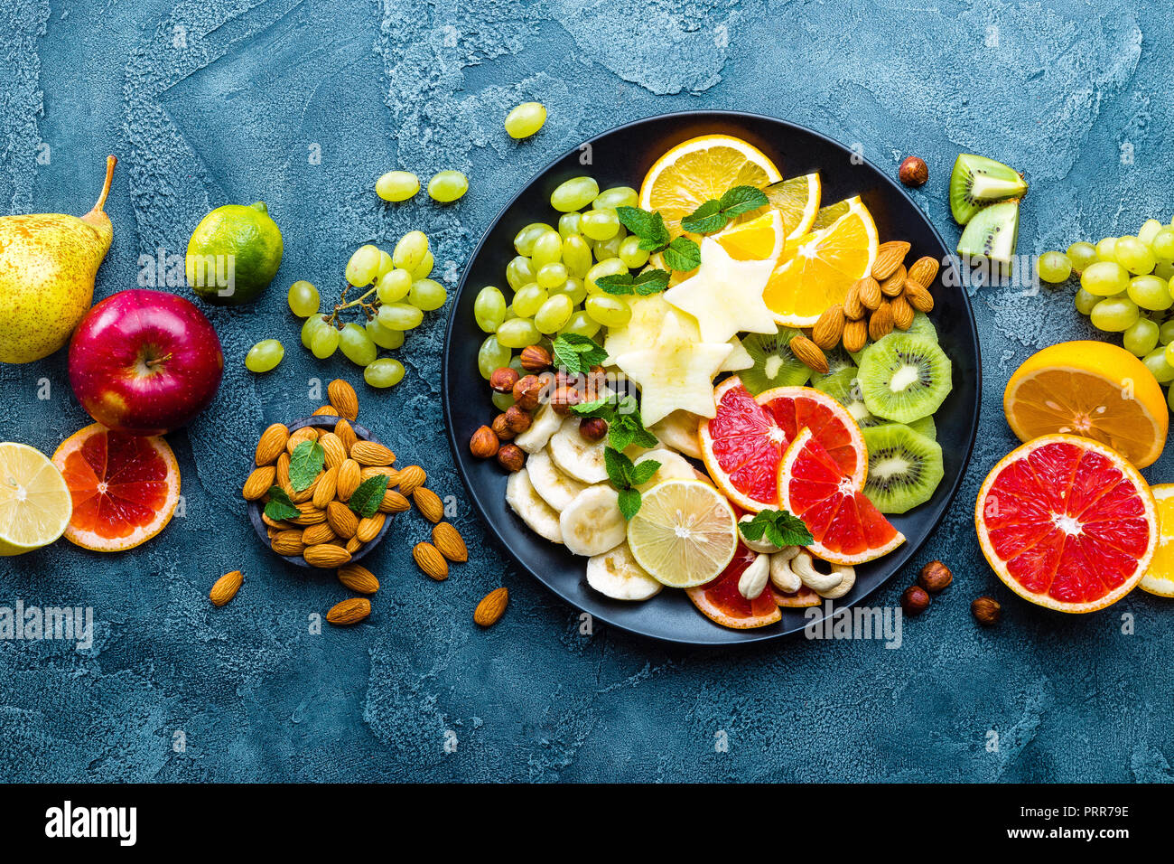 Sana ciotola vegetariano piatto con frutta fresca e i dadi. Piastra con raw apple, arancia, pompelmo, banana, kiwi, limone, uva e dadi Foto Stock