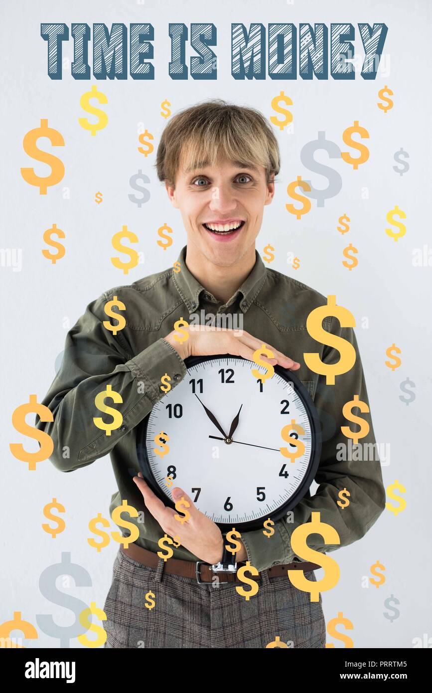 Imprenditore sorridente holding orologio da parete in mani su bianco con segni di dollaro battenti intorno Foto Stock