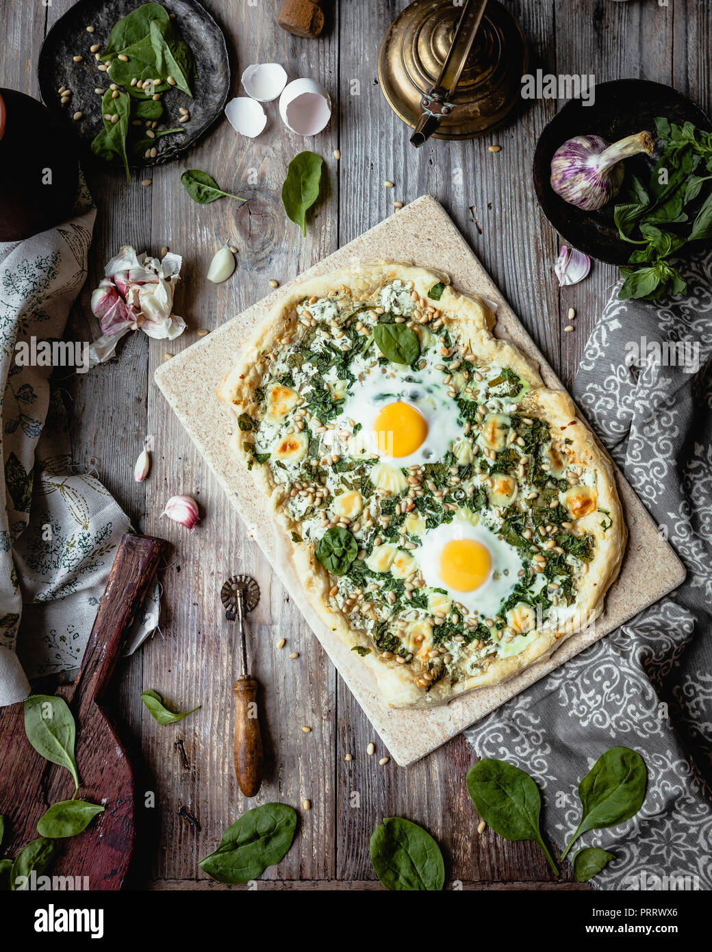Vista in elevazione della pizza fatta in casa con le uova e le erbe sul pannello di legno Foto Stock
