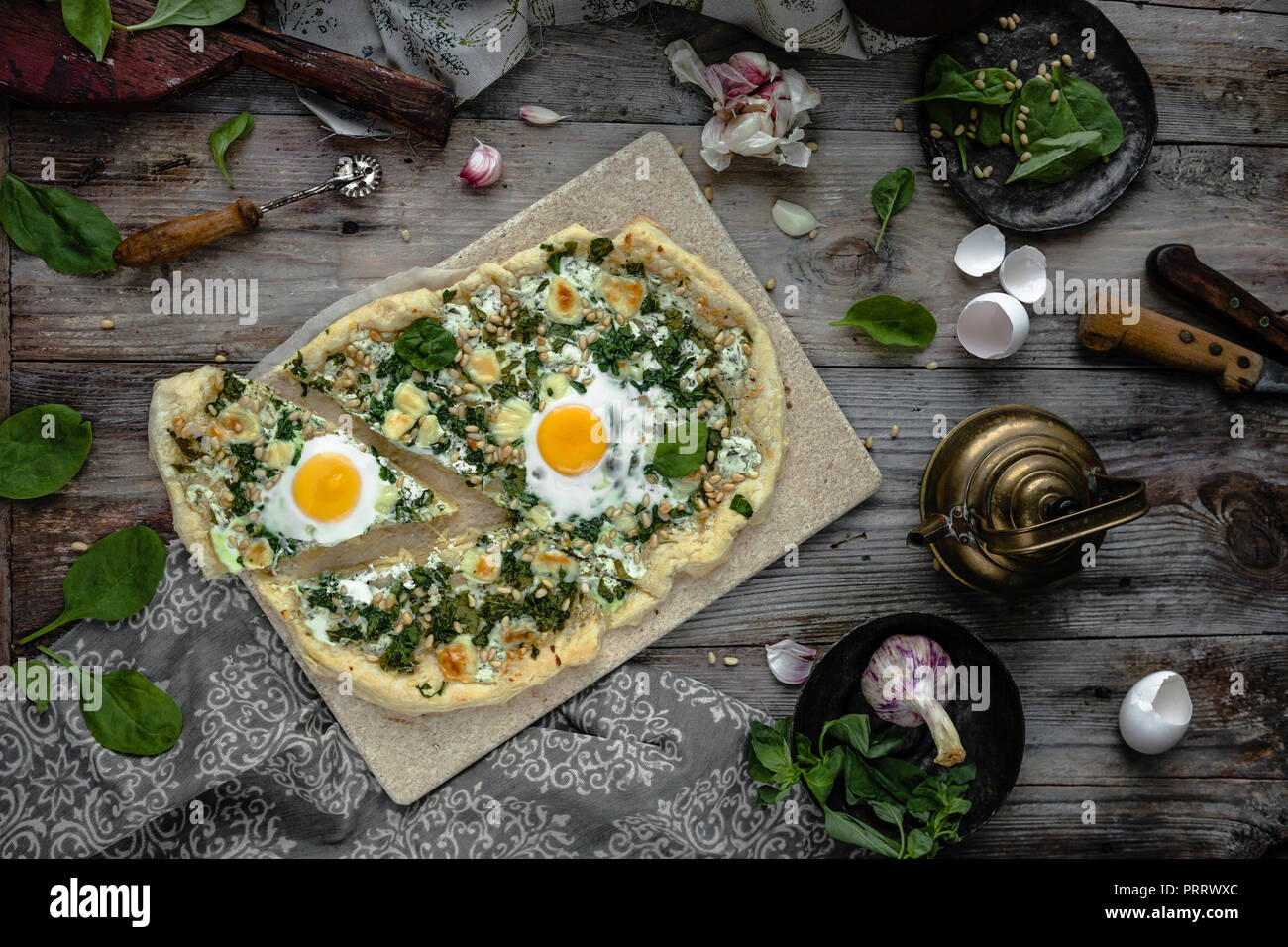 Vista superiore della pizza fatta in casa con le uova e le erbe sul pannello di legno Foto Stock