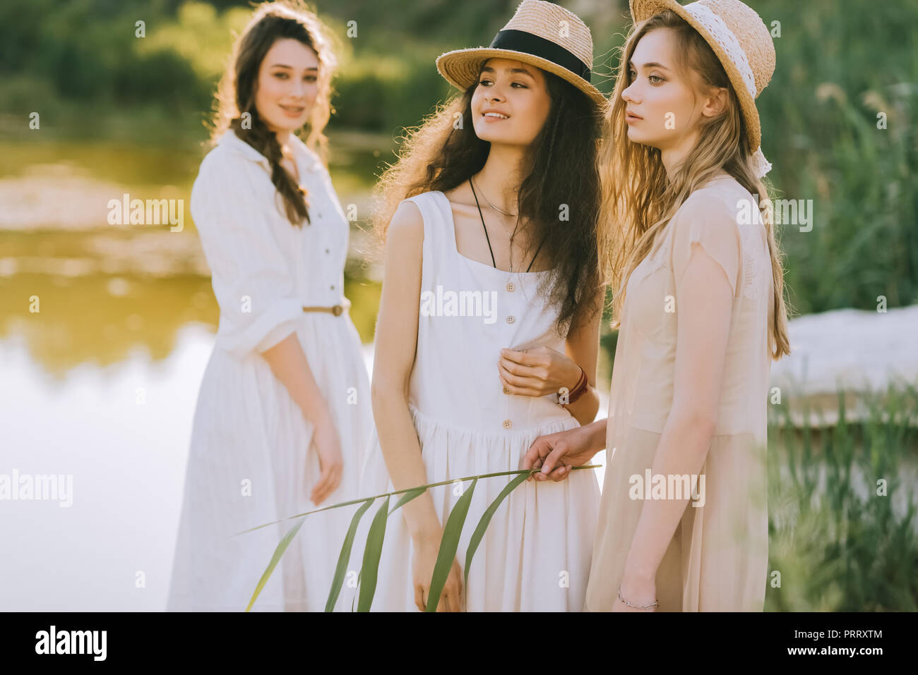 Felice ragazze attraenti in cappelli di paglia in piedi vicino al lago Foto Stock