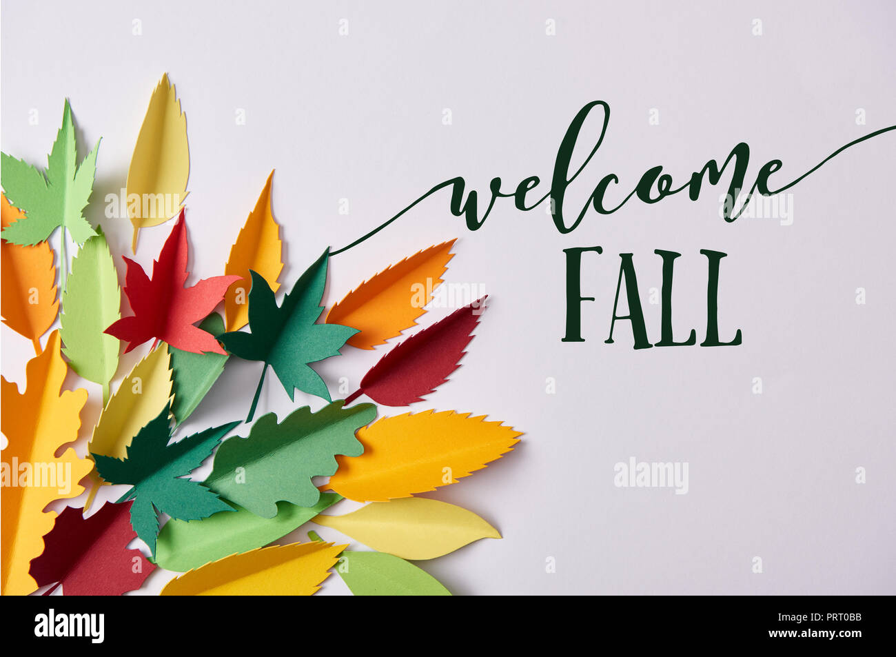 Lay piatto con colorate su carta a mano fogliame disposti su sfondo bianco con 'Benvenuto autunno' ispirazione Foto Stock