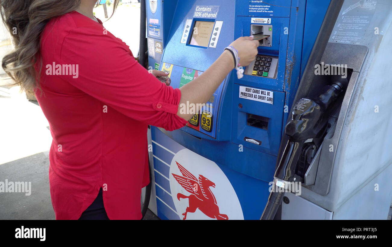 New York, Stati Uniti d'America - Circa 2018: donna non identificabili in maglietta rossa passare la carta di credito in Mobile della stazione di gas pompa carburante per pagare la benzina per riempire il serbatoio per auto Foto Stock