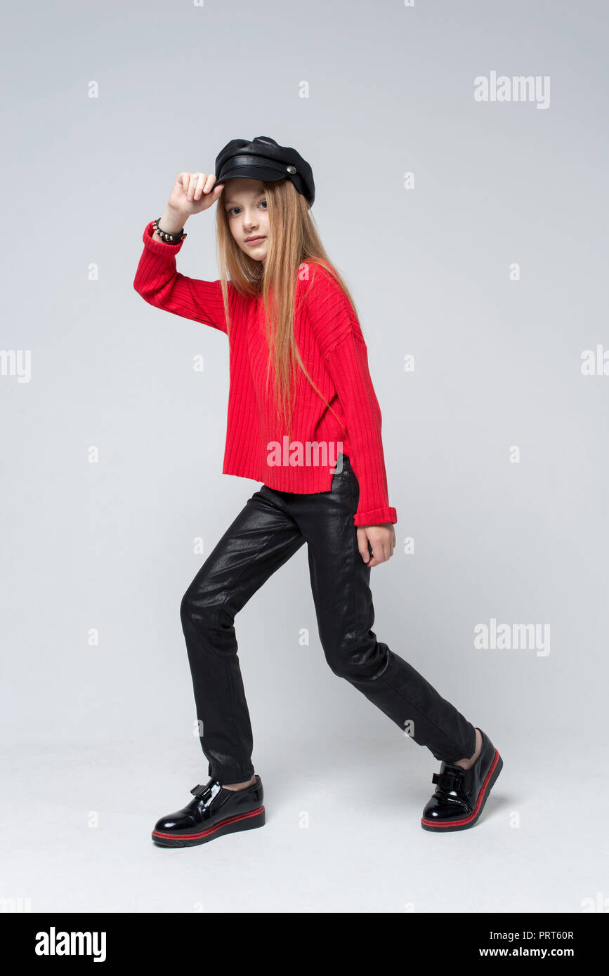 Ritratto di giovane e bella ragazza redhead che indossa un maglione rosso e pantaloni neri in posa di studio Foto Stock