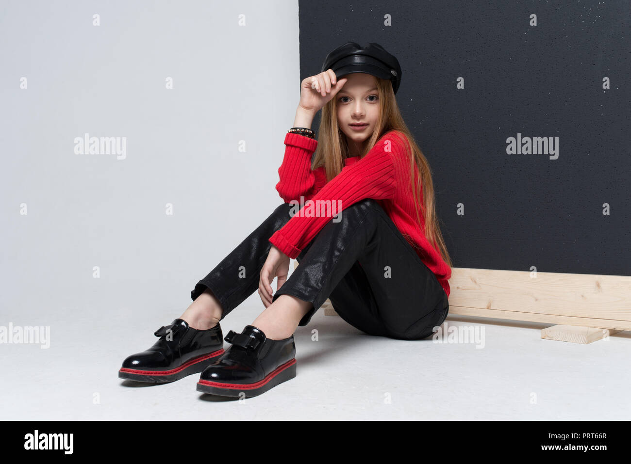 Ritratto di giovane e bella ragazza redhead che indossa un maglione rosso e pantaloni neri in posa di studio Foto Stock
