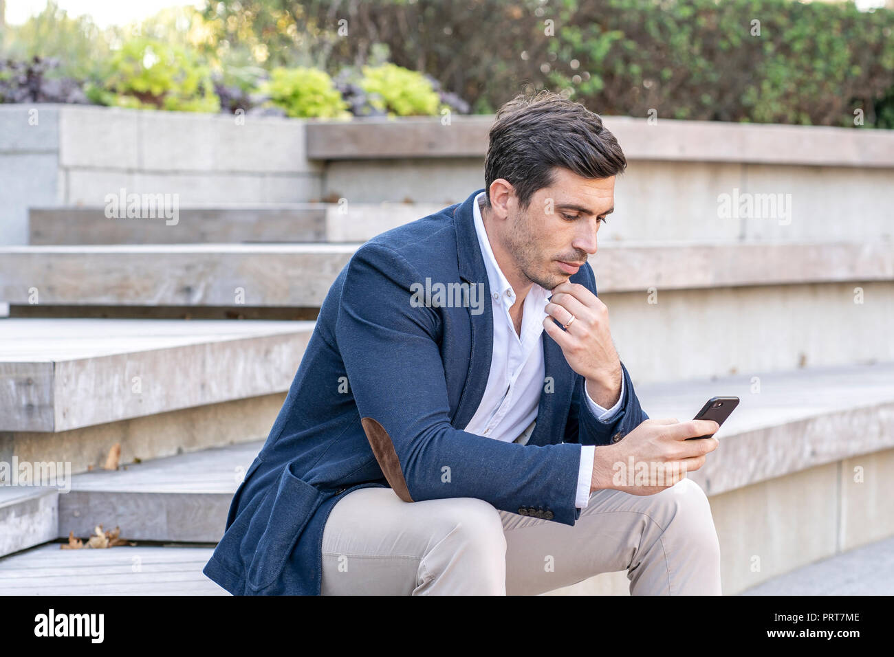 Attraente, imprenditore moderno a parlare e scrivere sul suo telefono cellulare. Imprenditore di successo facendo il lavoro. Foto Stock