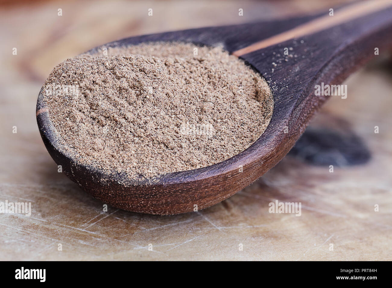 Di zucca in polvere in un cucchiaio di legno su un rustico sfondo di legno. Estrema profondità di campo con il fuoco selettivo. Foto Stock