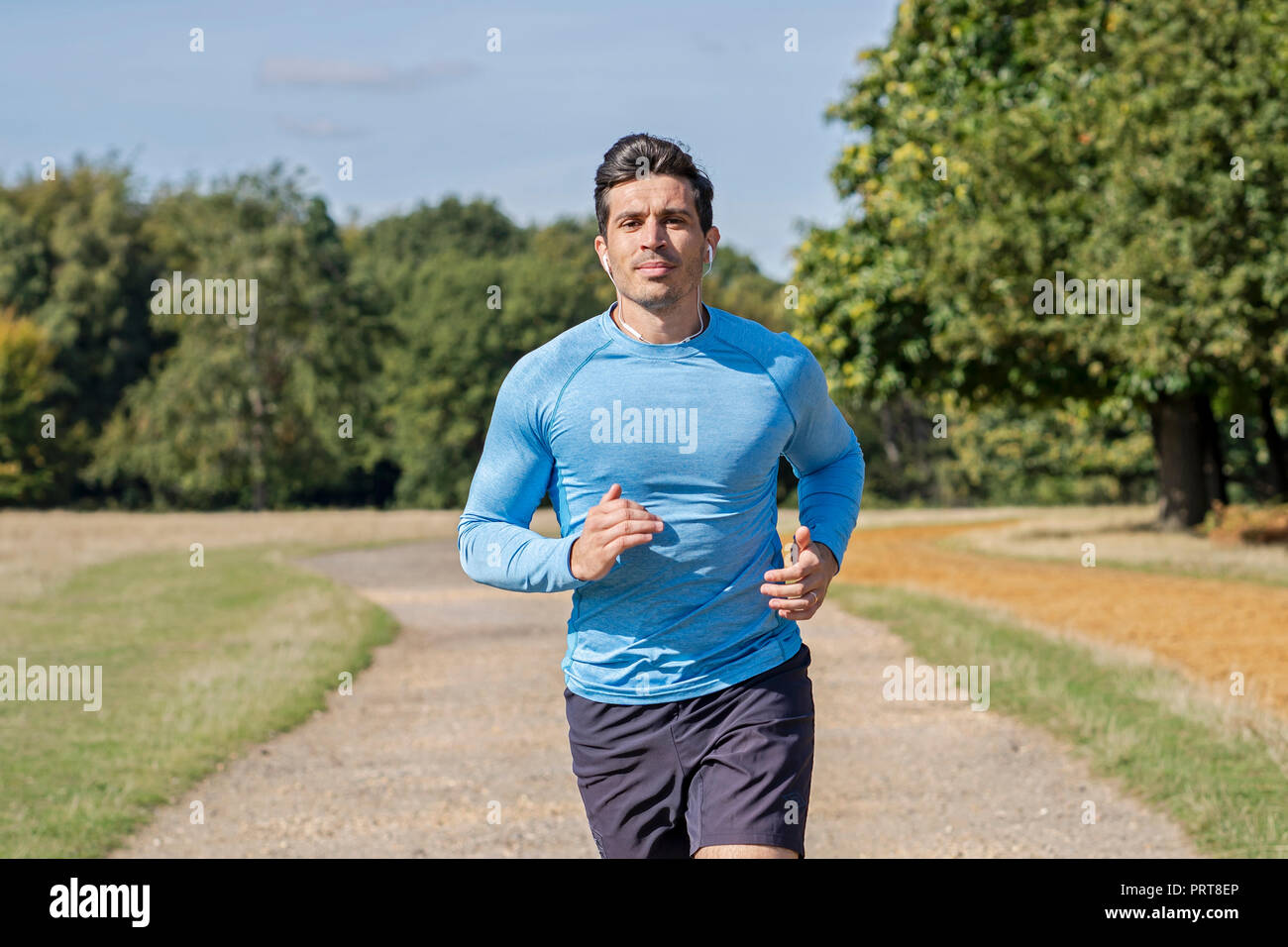 Attraente uomo a fare jogging nel parco. Personal Trainer in esecuzione e fare esercizio Foto Stock