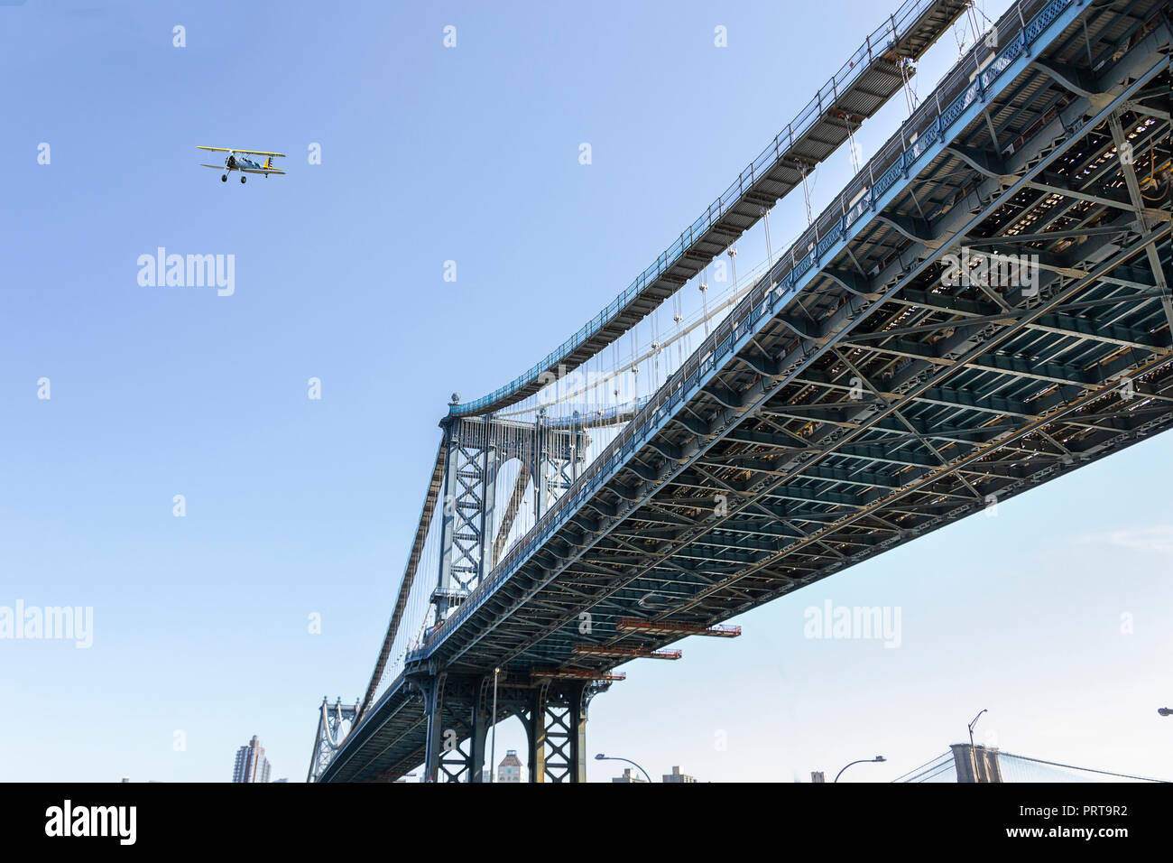 Un biplano volare sopra il ponte di Manhattan a New York Foto Stock