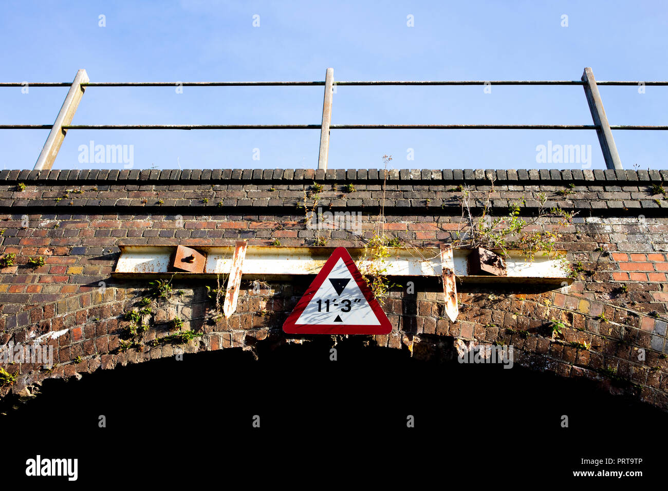 Limitazione altezza di firmare su arco in mattoni ponte ferroviario sulla strada di campagna Foto Stock