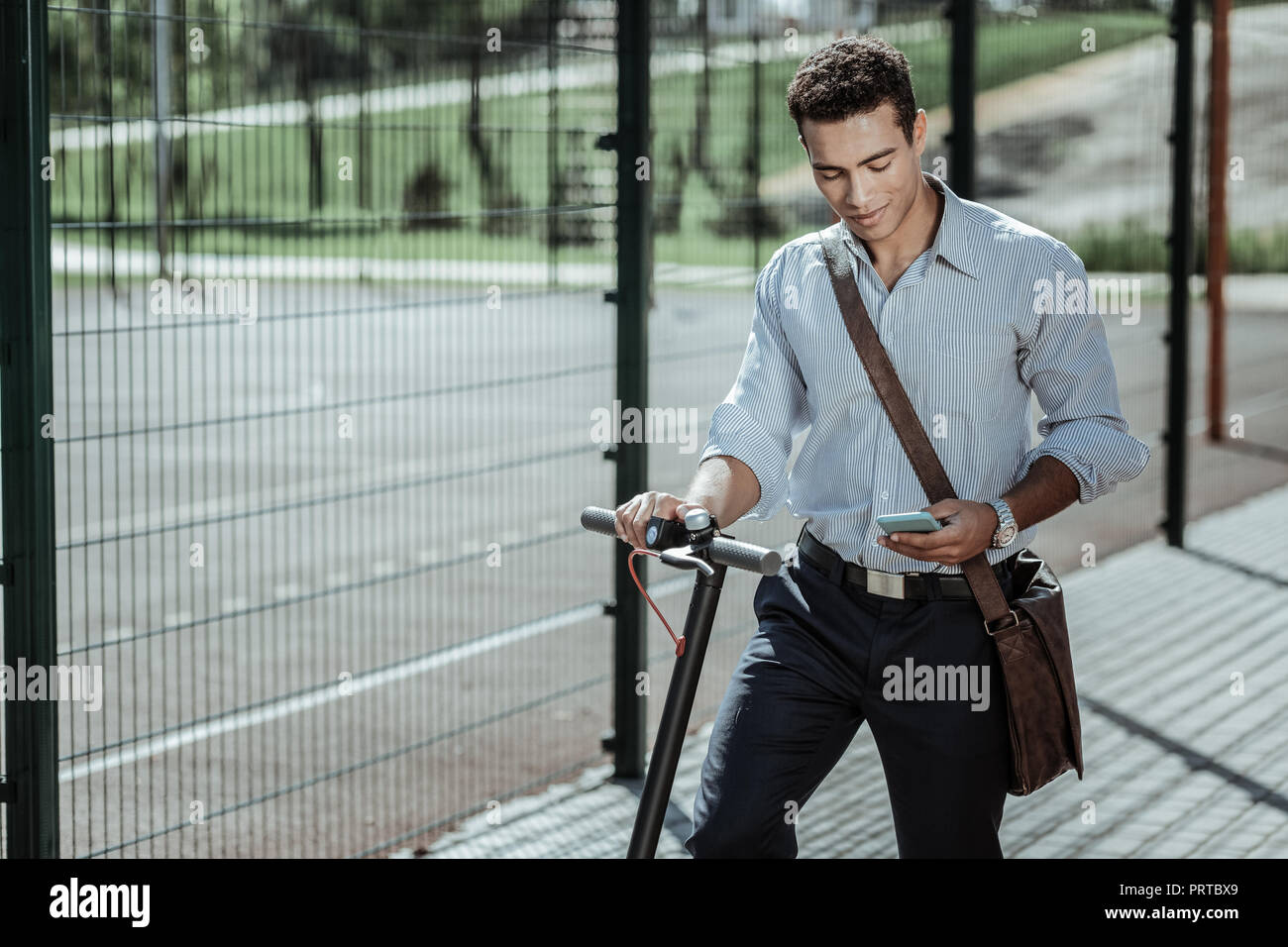 Felice fiducioso guy lanciare app per scooter elettrico Foto Stock