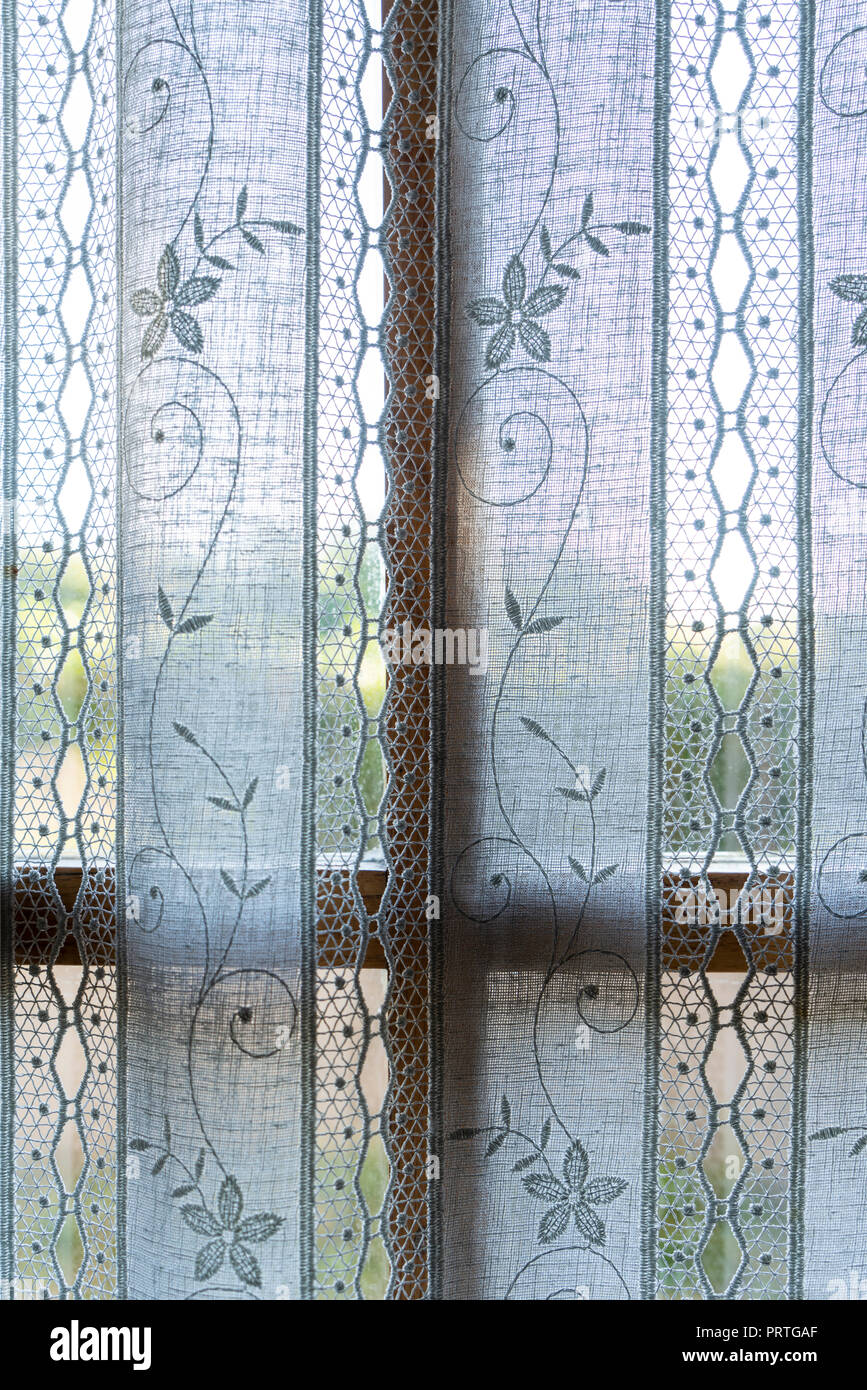 La finestra dietro una cortina ricamata Foto Stock
