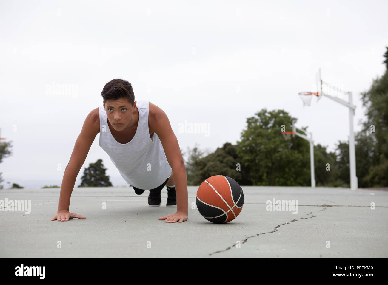Un adolescente di sesso maschile del giocatore di basket sul campo da pallacanestro facendo ups push Foto Stock