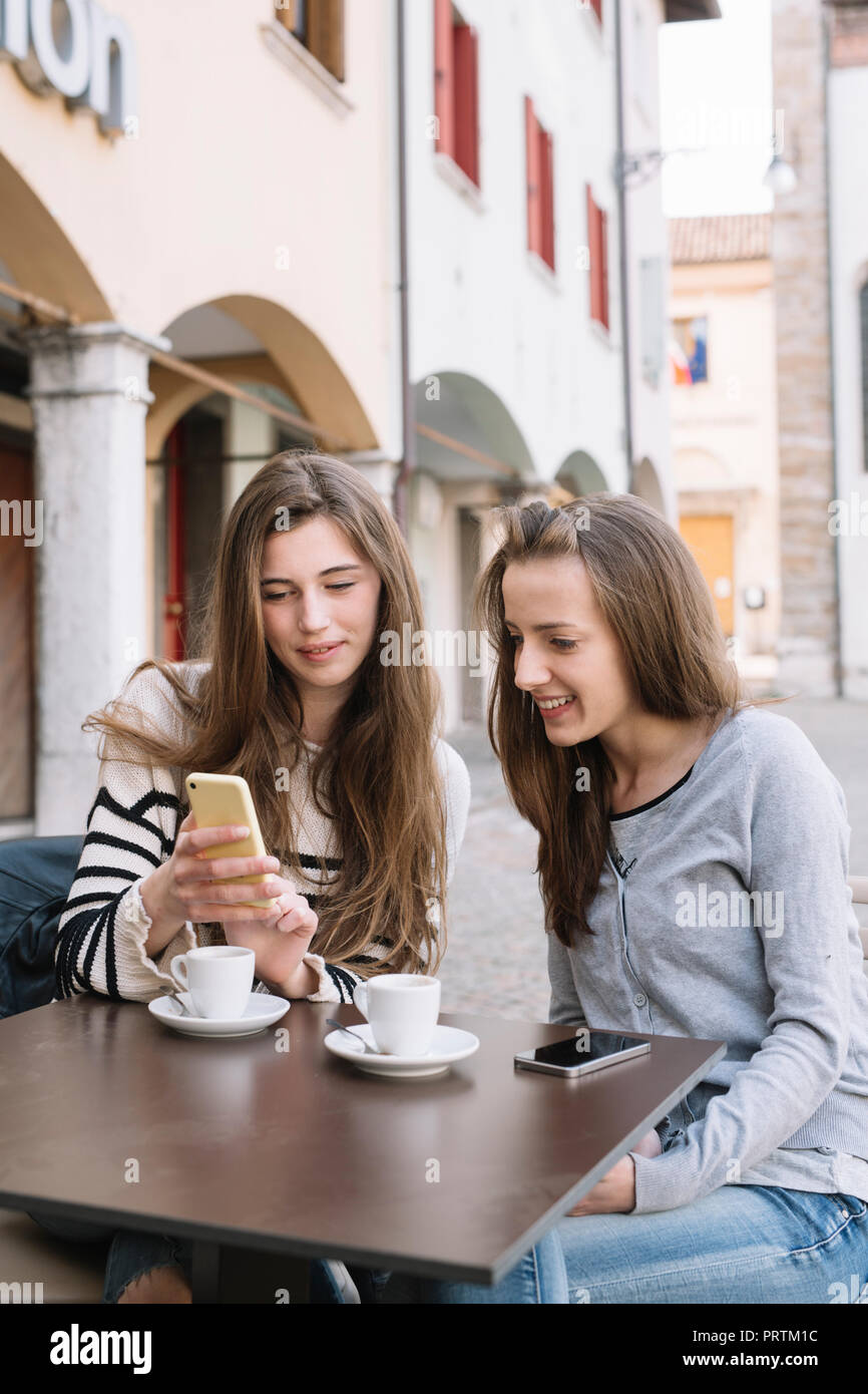 Fidanzate utilizzando il telefono cellulare presso il cafe, Belluno, Veneto, Italia Foto Stock
