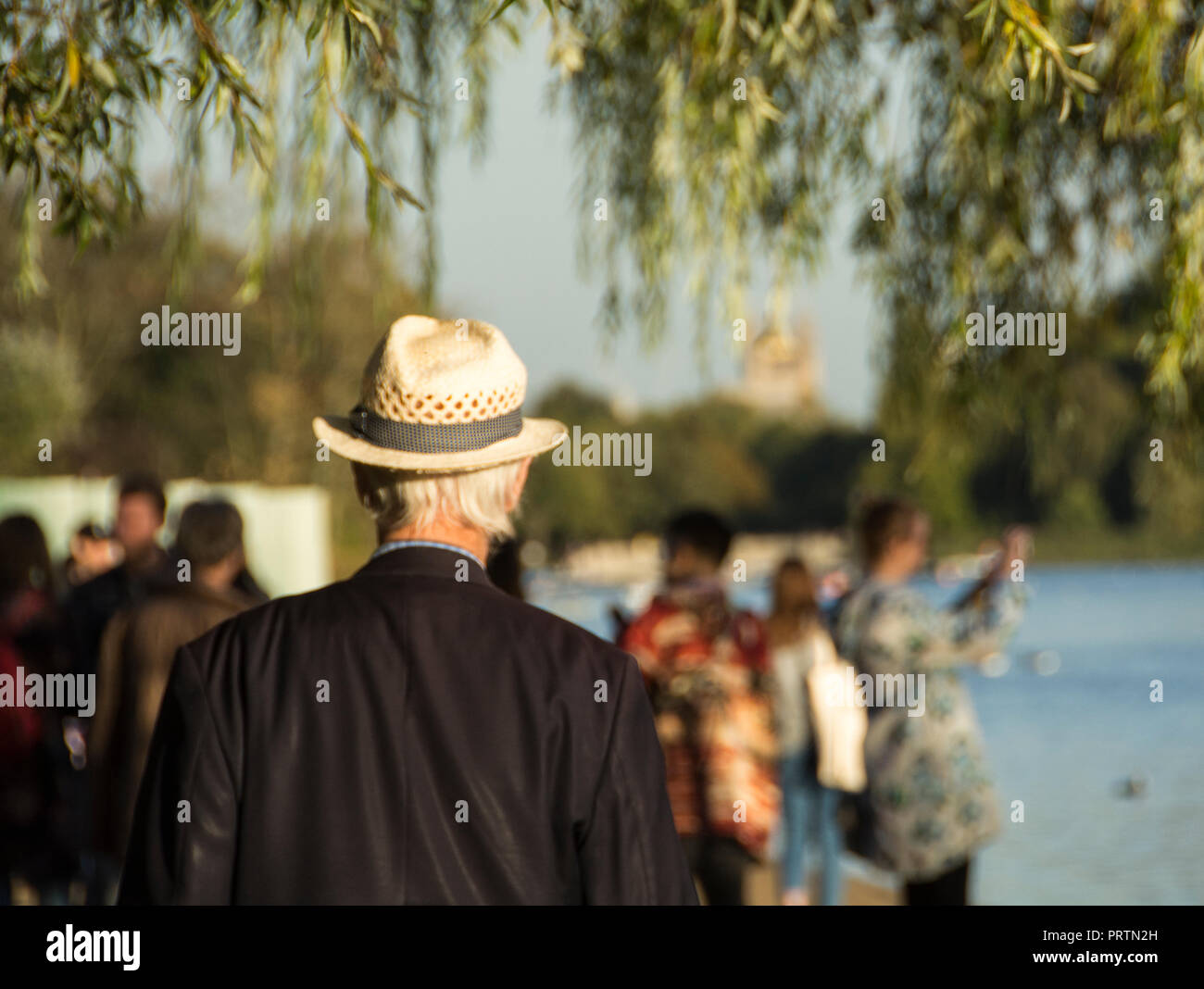Un anziano gentiluomo inglese, indossando un cappello di paglia, prende una passeggiata lungo le rive della serpentina all'Hyde Park di Londra, Regno Unito Foto Stock