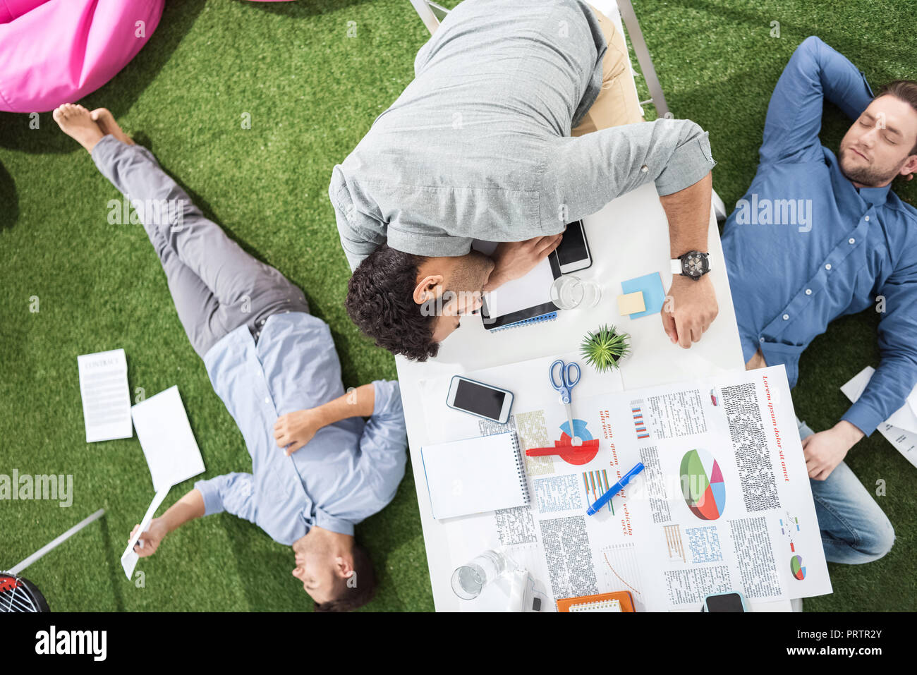 I giovani imprenditori di dormire sul tavolo e erba verde tappeto a ufficio moderno, business il lavoro di squadra Foto Stock