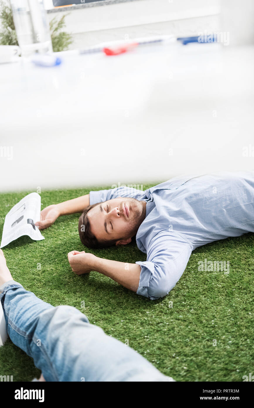 I giovani imprenditori di dormire su erba verde tappeto a ufficio moderno, business il lavoro di squadra Foto Stock