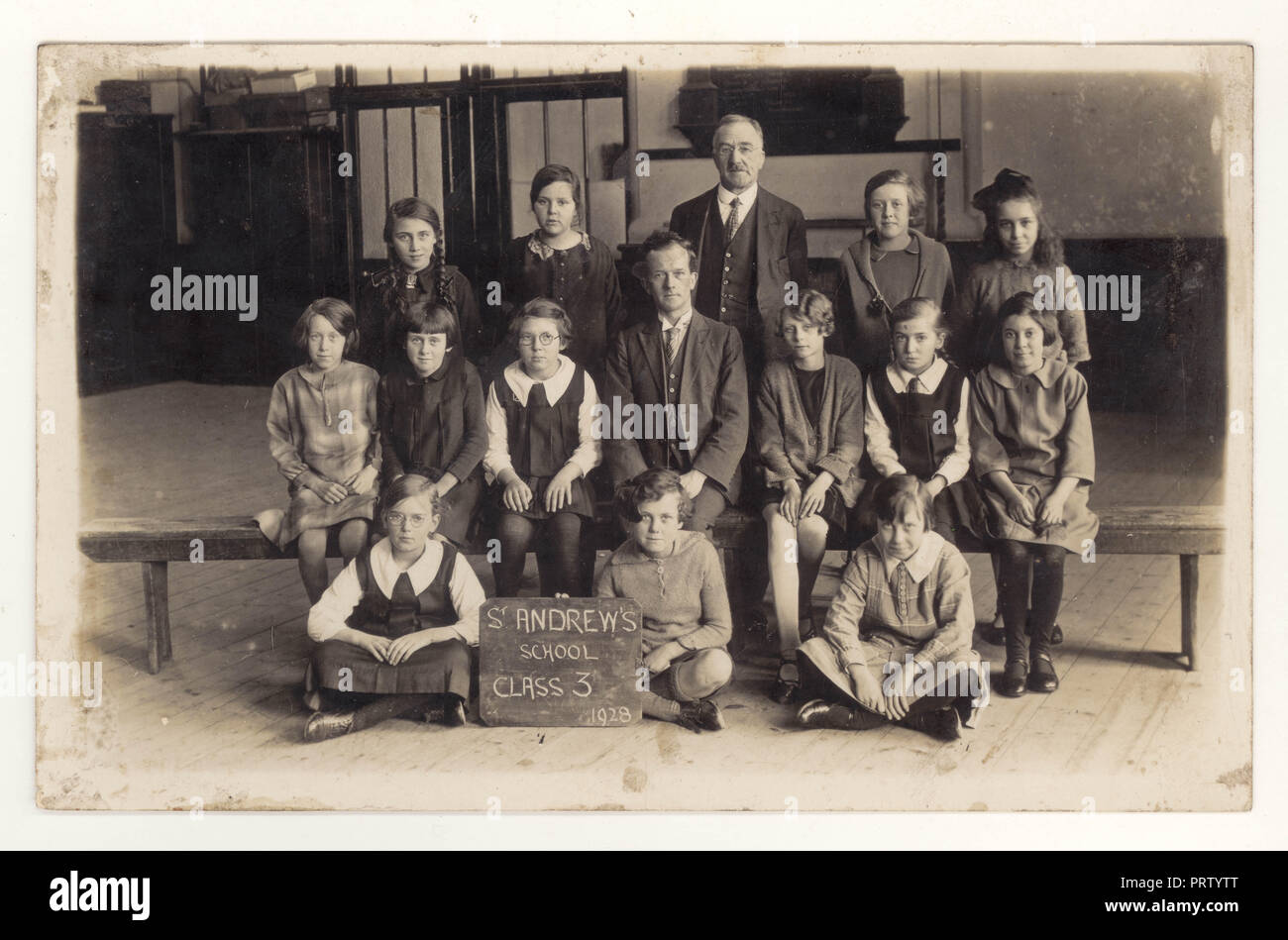 1920's cartolina di St Andrews Scuola classe 3, junior ragazze, in posa per una fotografia di classe con il loro insegnante, datata 1928, eventualmente a Sutton-in-Ashfield, Nottingham, Inghilterra, Regno Unito Foto Stock