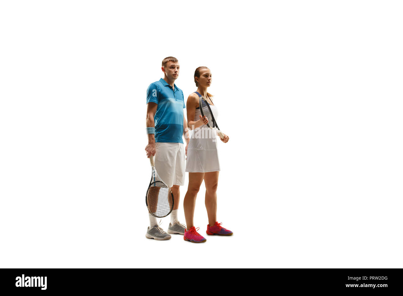 La Caucasian paio di maschio e femmina i giocatori di tennis in posa isolati su sfondo bianco. Studio shot di montare i giovani giocatori - uomo e donna in studio Foto Stock