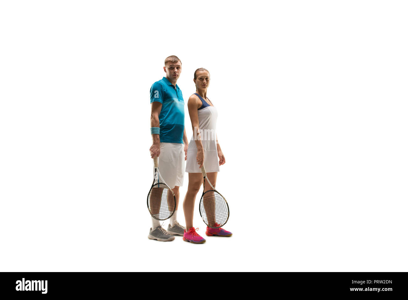 La Caucasian paio di maschio e femmina i giocatori di tennis in posa isolati su sfondo bianco. Studio shot di montare i giovani giocatori - uomo e donna in studio Foto Stock