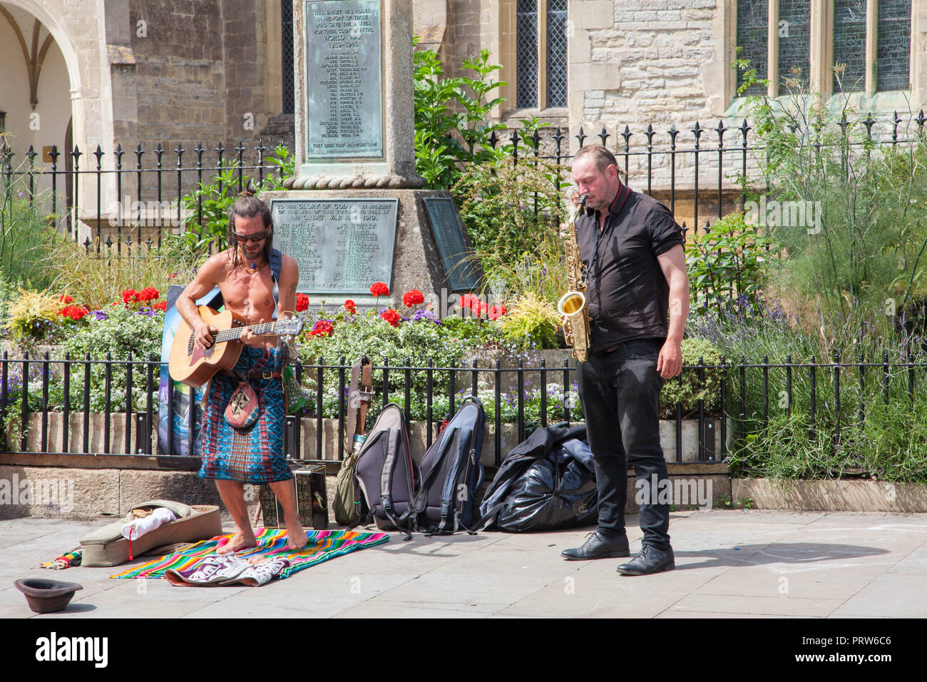 Artisti di strada buskers e musicisti preforma per il pubblico sul marciapiede della via principale di Glastonbury Inghilterra REGNO UNITO Foto Stock