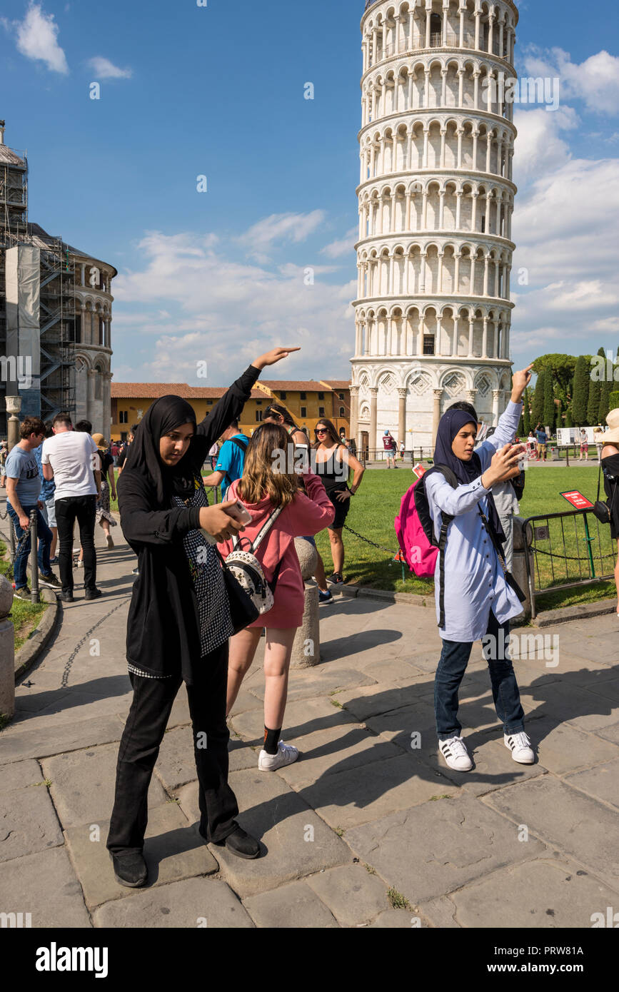 Due donne musulmane turisti tenendo selfie posa contro la Torre Pendente di Pisa, Toscana, Italia Foto Stock