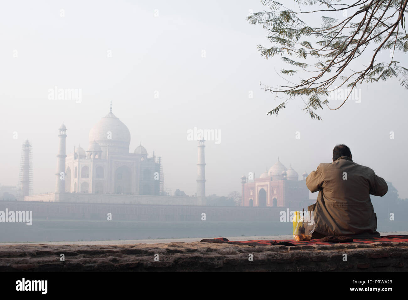 Taj Mahal la meraviglia del mondo e l'orgoglio di India in inverno mattina morbido e caldo con luce di haze e di un orologio seduta di guardia in primo piano Foto Stock