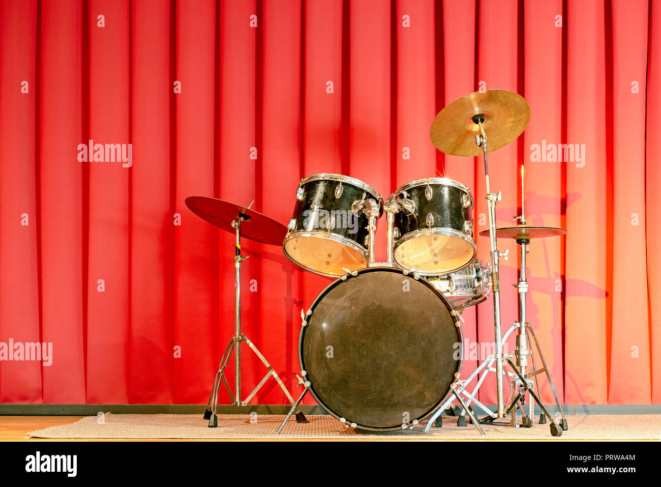 Drum set su una mostra di tappa con tende rosse Foto Stock