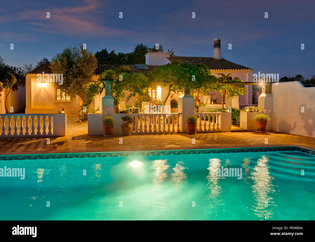 Un convertito Algarve rustico casa con piscina e terrazza con pergolato al crepuscolo, Portogallo Foto Stock