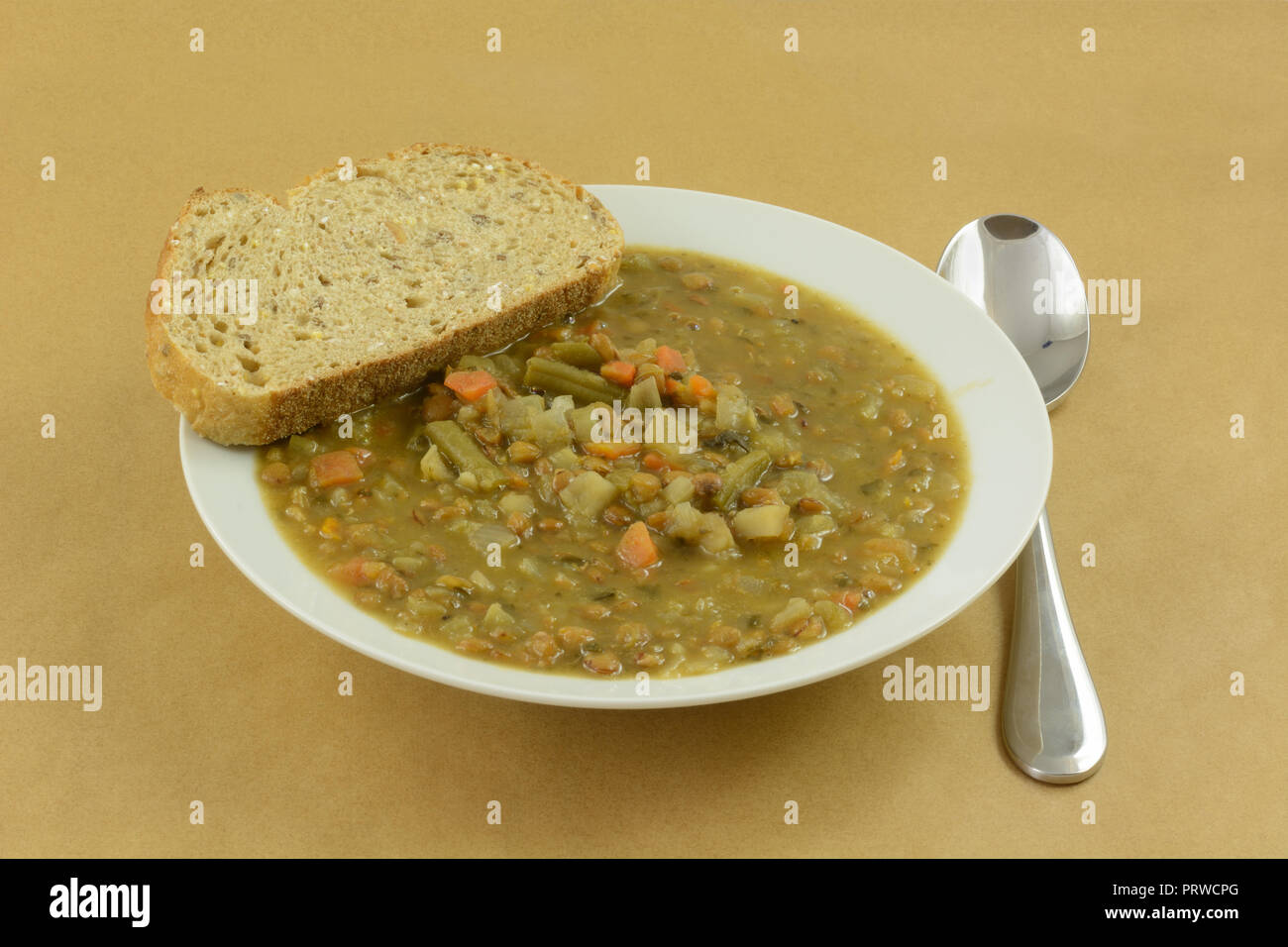Lenticchia minestra di verdura con fetta di pane bianco nella zuppiera con mestolo Foto Stock