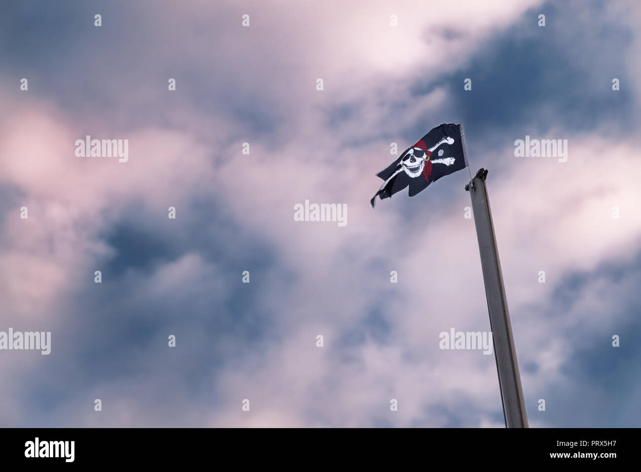Bandiera dei pirati sul montante contro il drammatico, rosso blu cielo molto nuvoloso Foto Stock