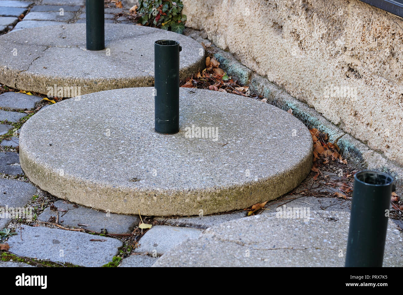 Grande ombrellone stabile stand con base in cemento lastre in piedi in una riga Foto Stock