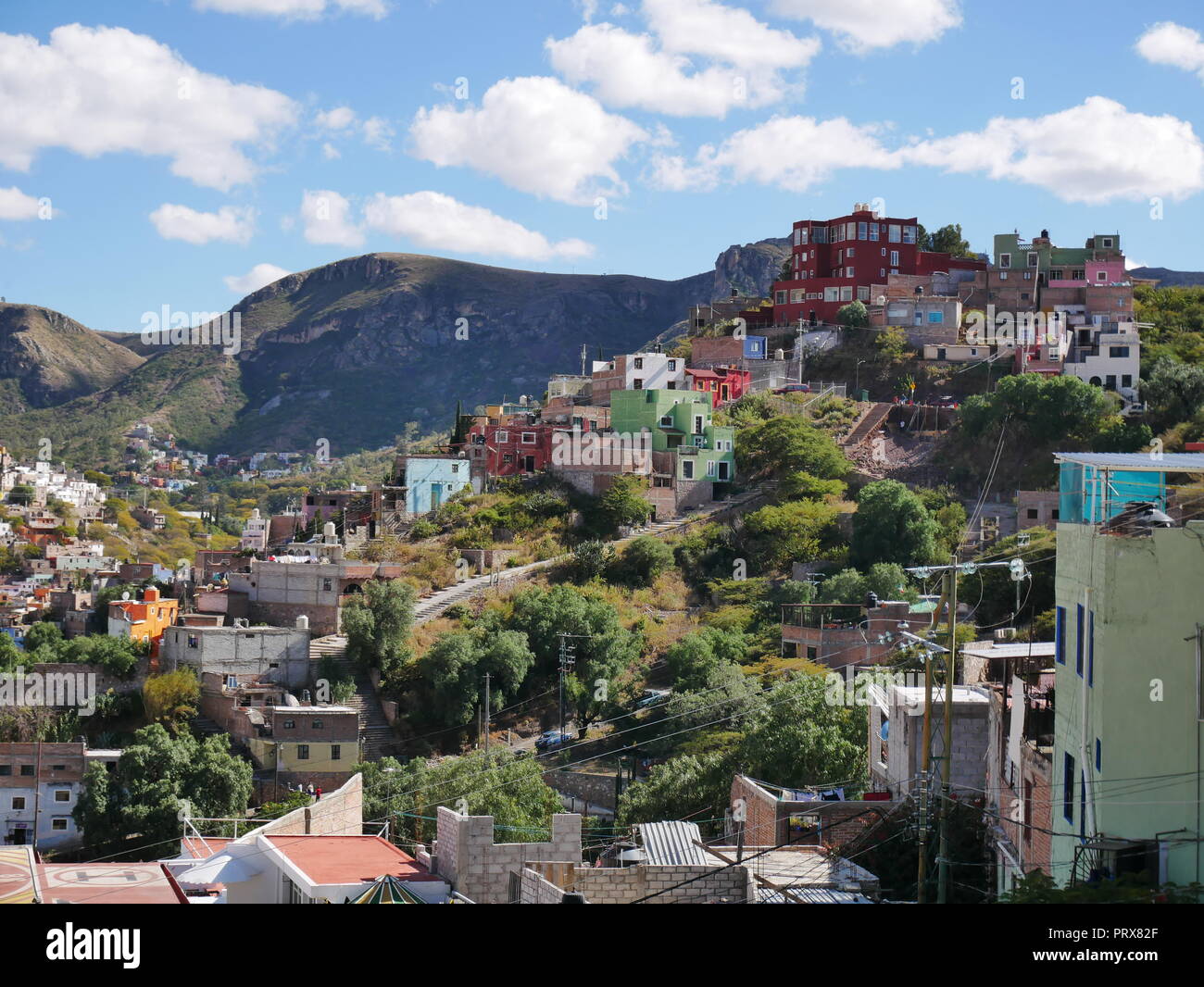 Alberi e case colorate costruito su una collina nella città di Guanajuato con la sierra in background, Messico Foto Stock