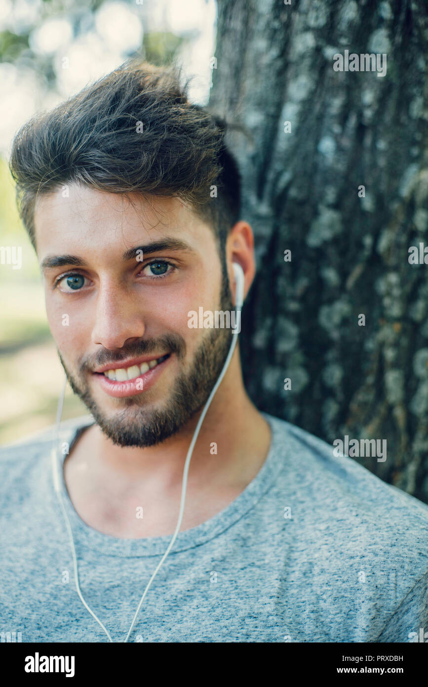 Close-up di sorridere giovane uomo ascoltare musica Foto Stock