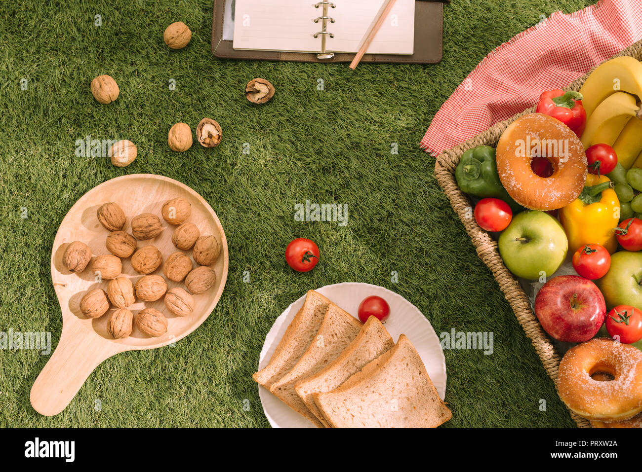 Picnic sull'erba. Rosso tovaglia controllati, basket, cibo sano panino e frutta, arancia, latte. Estate Tempo di riposo. Foto Stock