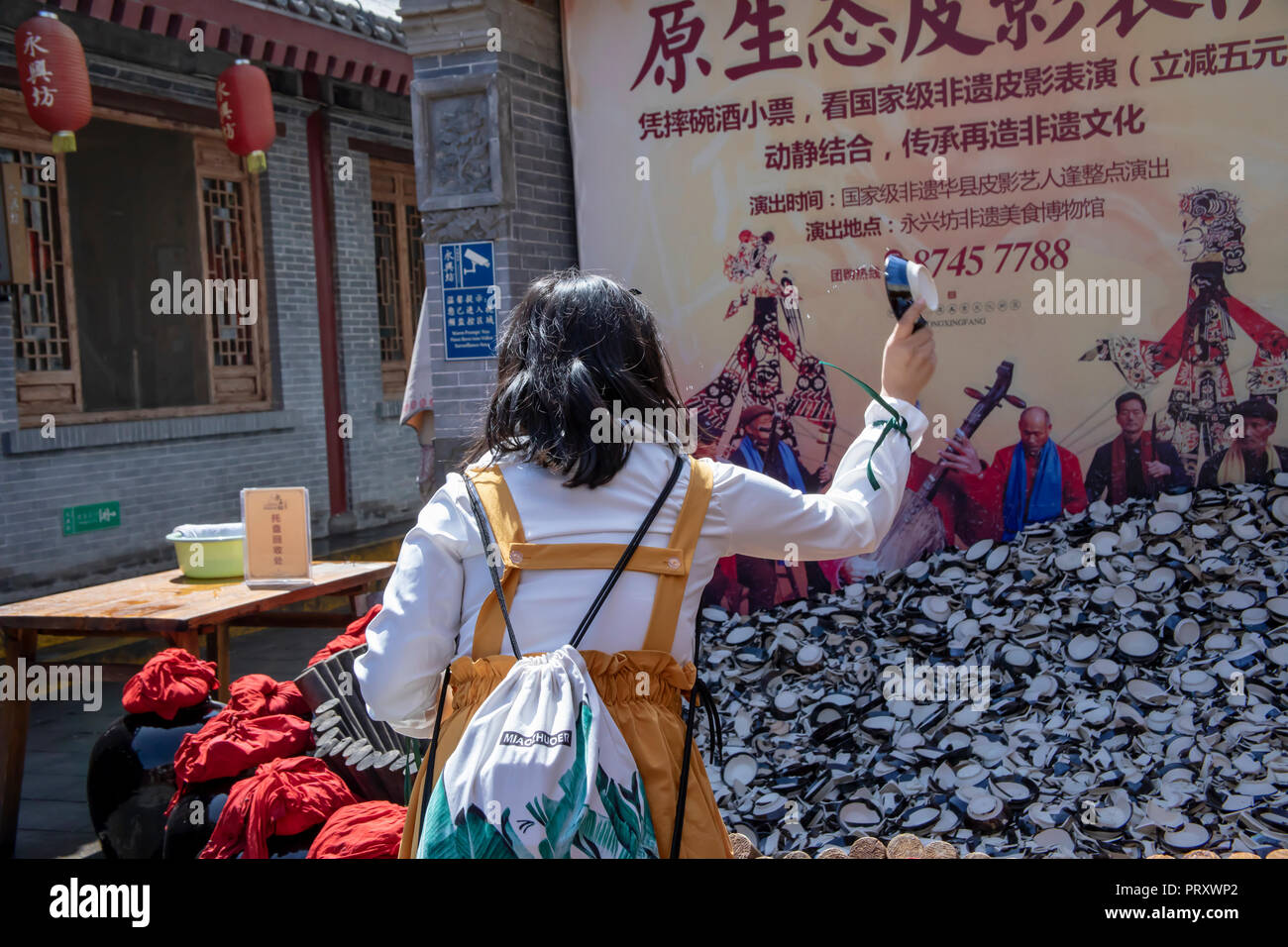 Xi'an, Shaanxi Province, Cina - 7 Settembre 2018 : Tourist bere il vino di riso provenienti dalla Cina tazze e smashing piatto per allontanare gli spiriti maligni in aperta ai Foto Stock