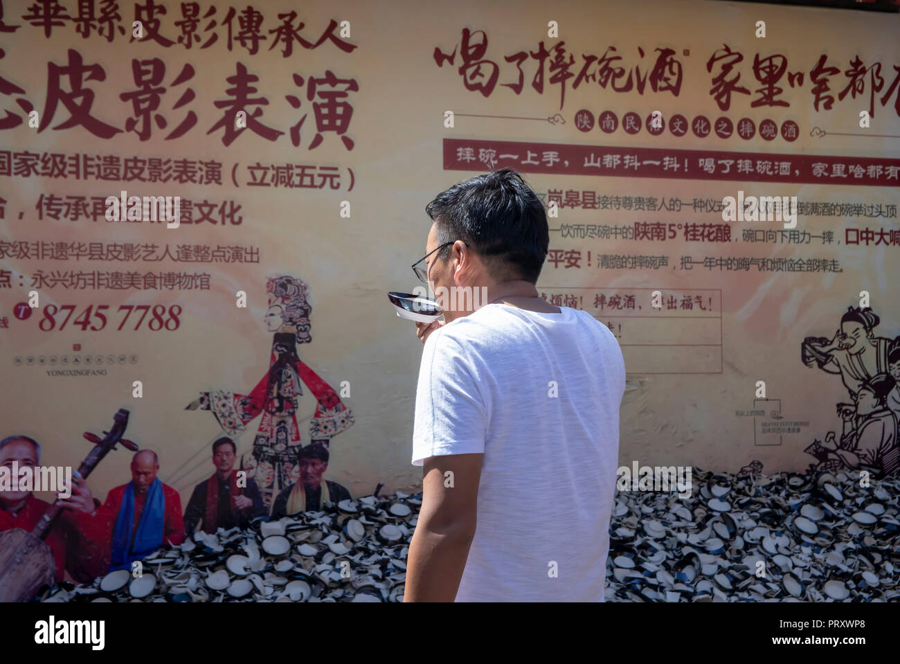 Xi'an, Shaanxi Province, Cina - 7 Settembre 2018 : Tourist bere il vino di riso provenienti dalla Cina tazze e smashing piatto per allontanare gli spiriti maligni in aperta ai Foto Stock