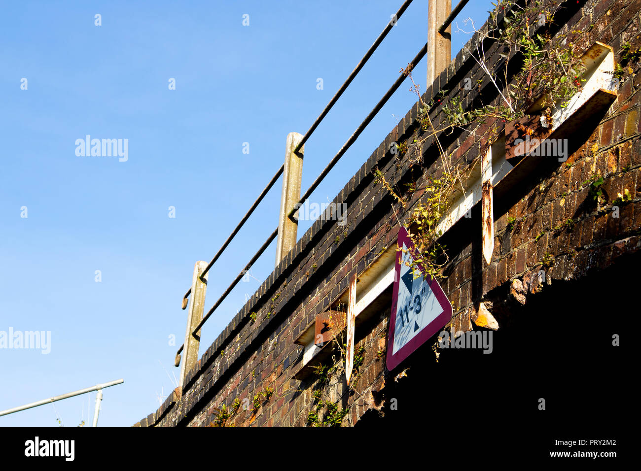 Limitazione altezza di firmare su arco in mattoni ponte ferroviario sulla strada di campagna Foto Stock